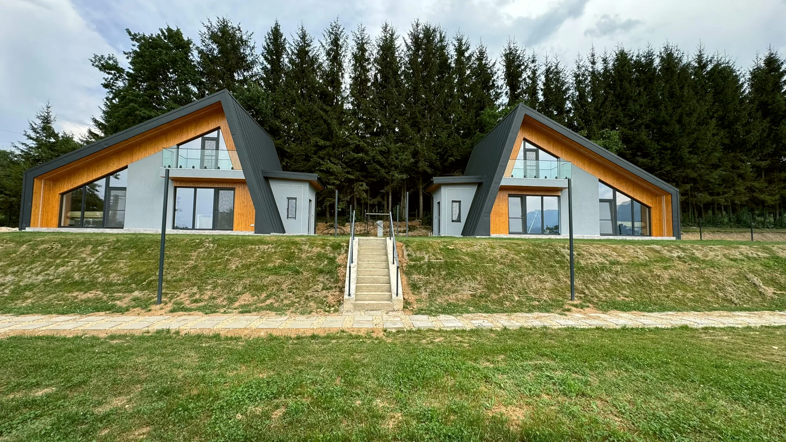 Cele două cabane identice, văzute din poiană
